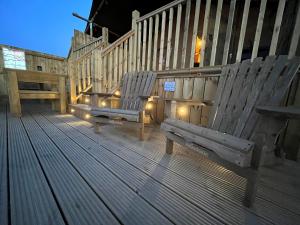two wooden chairs sitting on a deck with lights at Aladdin Safari Tent in Tenby