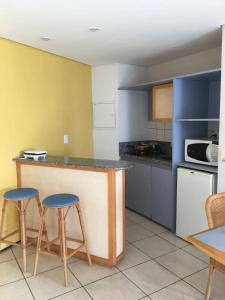 a kitchen with two bar stools and a counter top at PRAIA DE MUCURIPE - FRENTE MAR - Ap205 in Fortaleza