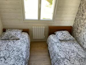 2 łóżka w małym pokoju z oknem w obiekcie Maison familiale et cosy w mieście Roscanvel