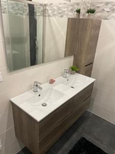 La salle de bains est pourvue d'un lavabo blanc et d'un miroir. dans l'établissement Maison familiale et cosy, à Roscanvel
