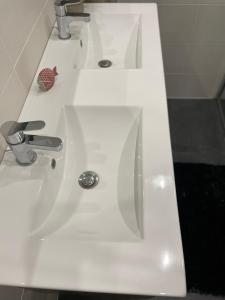 La salle de bains est pourvue d'un lavabo blanc et d'un robinet. dans l'établissement Maison familiale et cosy, à Roscanvel