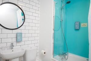 a bathroom with a shower and a sink and a mirror at Highwayman Hotel in Dunstable