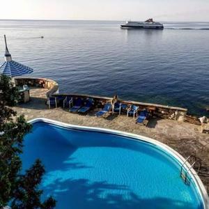 uma grande piscina junto à água com um barco em Daidalos Hotel em Armenistís