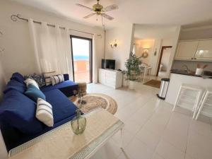 a living room with a blue couch and a kitchen at Paradise Seaview Apartment in Adeje