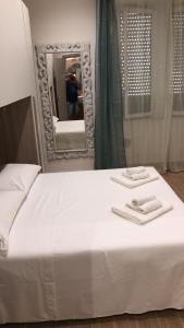een bed met twee handdoeken en een spiegel bij Antico Hotel Moderno in Piombino