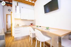 uma cozinha com armários brancos e uma mesa com cadeiras brancas em Pisa Tower Apartment em Pisa