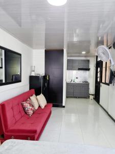 un salon avec un canapé rouge et une cuisine dans l'établissement Apartaestudio ROMA 402 Edificio Europa Ibagué, à Ibagué