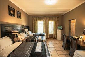 um quarto de hotel com duas camas e uma secretária em Ramandire B&B em Witbank
