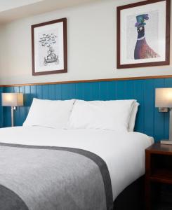a bed in a hotel room with two pictures on the wall at Highwayman Hotel in Dunstable