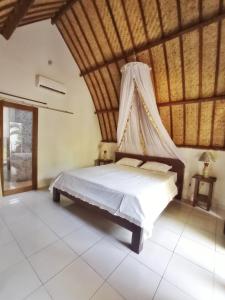 a bedroom with a bed with a mosquito net at Follow The Rabbit Bungalow in Gili Air