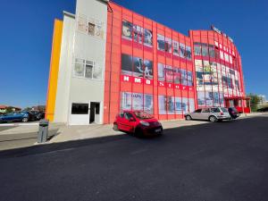 a red building with two cars parked in front of it at Apartament ELLA in Tulcea