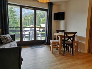 ein Wohnzimmer mit einem Tisch und Stühlen sowie einem Balkon in der Unterkunft Duo Des Alpages vue exceptionnelle sur le Mont Blc in Saint-Gervais-les-Bains