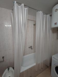 a bathroom with a white shower curtain and a toilet at Guest House Tomba in Bar