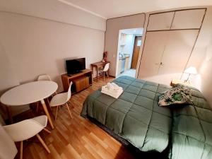Un dormitorio con una cama y una mesa y sillas. en Center 208 - DAT (Habilitación 170/2018), en San Carlos de Bariloche