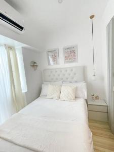 a white bedroom with a white bed with two pillows at Victoria Sports Tower - Cozy Ambiance Condo Unit in Manila