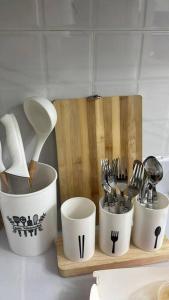 four white cups and utensils on a wooden shelf at Victoria Sports Tower - Cozy Ambiance Condo Unit in Manila