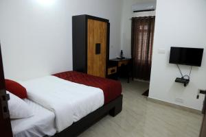 a bedroom with a bed and a desk and a television at NIDHI RESIDENCY in Guruvāyūr +15 photos