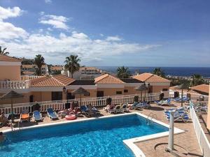 a resort swimming pool with chairs and the ocean at Paradise Seaview Apartment in Adeje