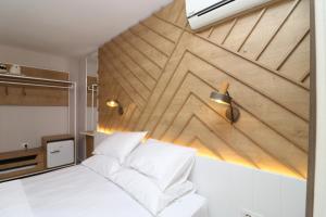 a bedroom with a white bed and a wooden wall at Hercules Room in Himare