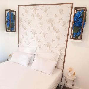 1 cama con almohadas blancas y una pared con flores en Résidence Prestige, Calme & Terrasse Ensoleillée en Grenoble