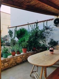 Cozy apartment in Peania (near Airport) في Paianía: طاولة خشبية في فناء مع نباتات الفخار