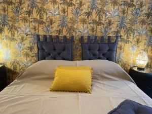a bed with a yellow pillow on top of it at Les Remparts Antibes Location in Antibes
