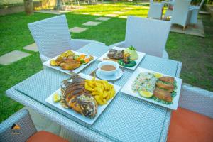 une table avec plusieurs assiettes de nourriture dans l'établissement CWEZI BY THE LAKE, à Entebbe