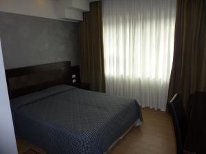 een slaapkamer met een bed en een raam met gordijnen bij Alla Bianca Hotel in Marghera