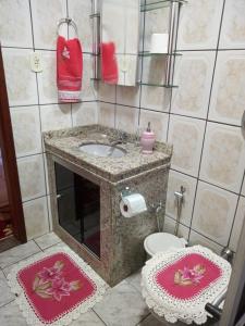 a bathroom with a sink and a toilet with mats at CASA DA LÉIA in Alto Caparao