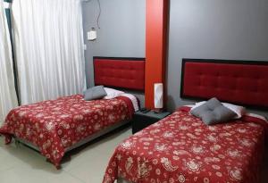 a bedroom with two beds with red covers at Amaris Hotel in Ica