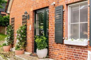a brick house with a black door and potted plants at Traumferienwohnung in der Lüneburger Heide in Soltau