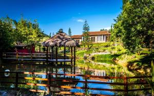 a pond with a gazebo and a house at Encantos do Vale Pousada e SPA Cultural in Bueno Brandão