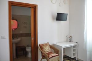 Zimmer mit einem Stuhl, einem Schreibtisch und einem TV in der Unterkunft Sisters house in Lecce