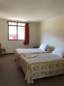 two beds in a room with a window at Hotel Las Vicuñas in Putre