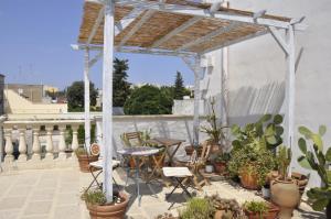 eine Terrasse mit einem Tisch, Stühlen und Topfpflanzen in der Unterkunft Sisters house in Lecce
