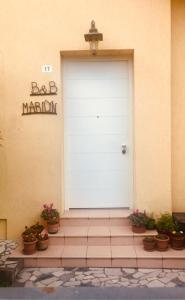 B&B MARILYN في رافينا: باب أبيض على مبنى به نباتات الفخار