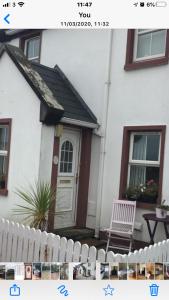 una casa blanca con una puerta blanca y una silla en Stable View, Clara Meadows Dunfanghy, en Dunfanaghy