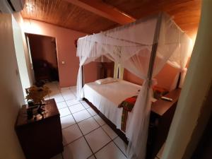 ein Schlafzimmer mit einem weißen Bett mit Baldachin in der Unterkunft LA MARINA in Ambodifototra
