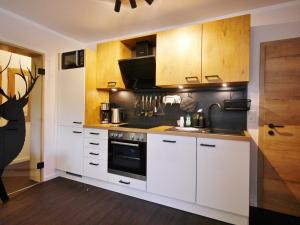 a kitchen with white cabinets and a stove at Upland Apartments - Fewo Waldgeist (inkl. MeineCardPlus) in Willingen