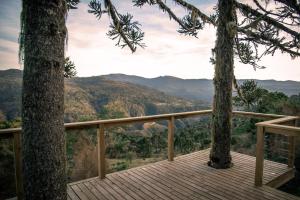 a wooden deck with two trees and mountains in the background at Rancho Denver in Urubici