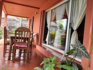 eine Veranda mit einem Tisch, Stühlen und einem Fenster in der Unterkunft LA MARINA in Ambodifototra