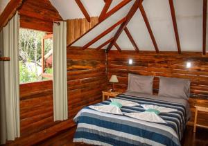 a bedroom with a bed in a room with wooden walls at Chale Canto dos Cristais in Visconde De Maua