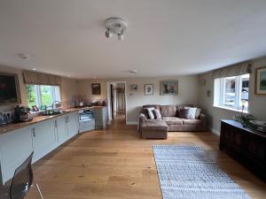 a large living room with a couch and a kitchen at A modern annex, in a tranquil countryside setting. in Aylesbury