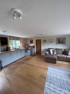 a living room with a couch and a kitchen at A modern annex, in a tranquil countryside setting. in Aylesbury