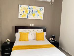 Un dormitorio con una cama con almohadas amarillas y una pintura en Studio de haut standing, Bonamoussadi (Kotto), en Douala