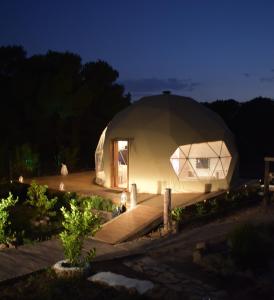 una gran tienda de campaña en una cúpula en un jardín por la noche en Domo Suites Masía Cal Geperut, en Badalona