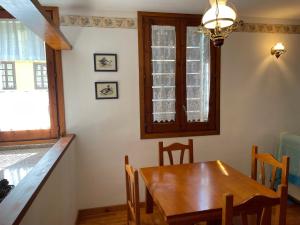 a dining room with a wooden table and a window at Apartaments Pirinenc in Esterri d'Àneu