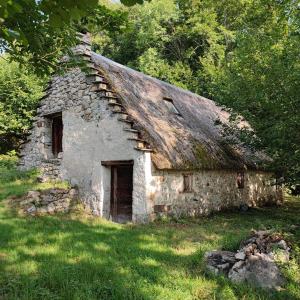 an old stone house with a roof in the grass at Grand appartement en RDC Vallée de Campan in Campan