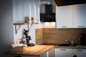 a kitchen with white cabinets and a wooden counter top at Pstrowskiego 13 in Olsztyn