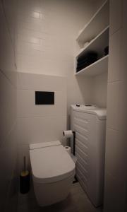 a white bathroom with a toilet and a shelf at Pstrowskiego 13 in Olsztyn